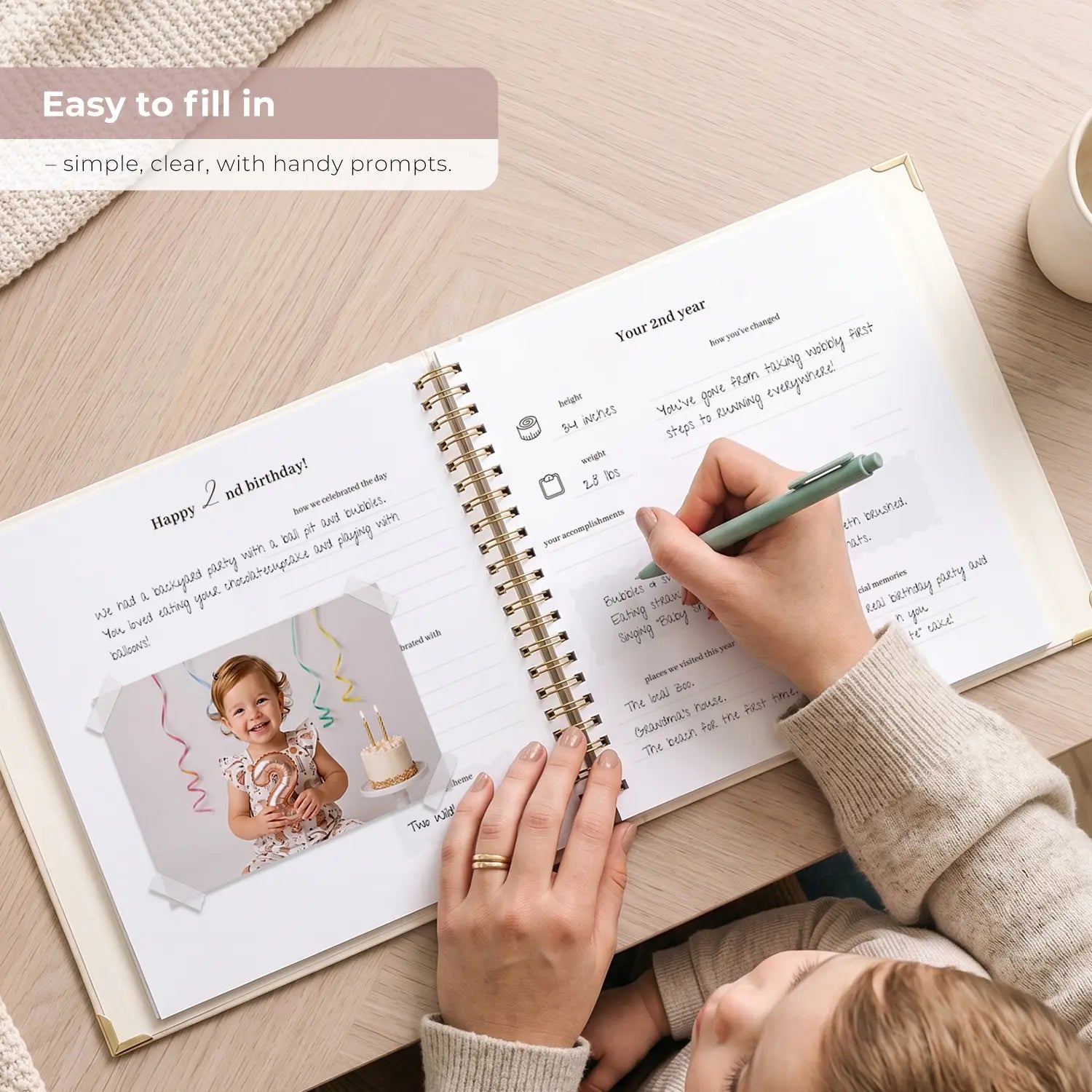 A mother writing in the Hello Baby memory book, showcasing the easy-to-fill-in interior pages featuring clear, handy writing prompts for effortless toddler milestone tracking.