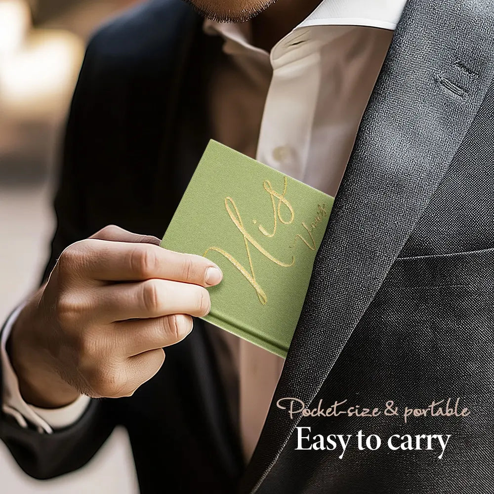 A groom securely tucking the portable sage green Molekaus 'His Vows' booklet, featuring elegant gold cursive lettering, into his inner suit jacket for an easy-to-carry wedding day experience.