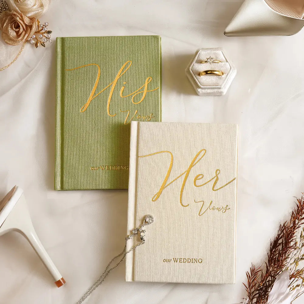 A romantic wedding morning flat lay showcasing the Molekaus sage green and white linen 'His and Her Vows' book set, elegantly styled alongside a velvet ring box, bridal heels, and delicate jewelry on soft sheer fabric.
